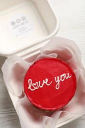 Photo of Bento cake with Love You text in takeaway box on white wooden table, top view. St. Valentine's day surprise