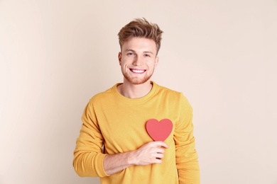 Photo of Portrait of young man with paper heart on color background