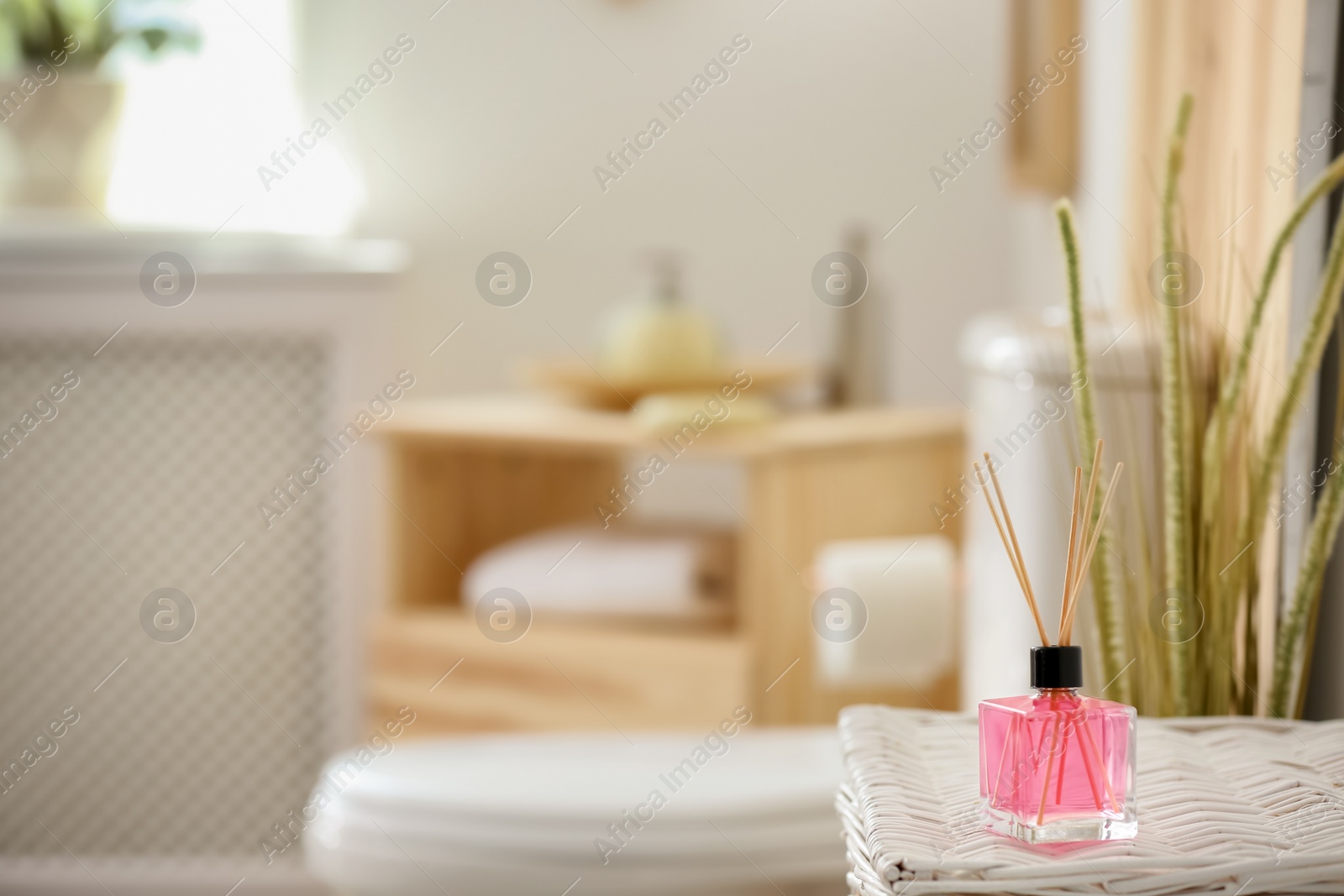 Photo of Aromatic reed air freshener on table against blurred background