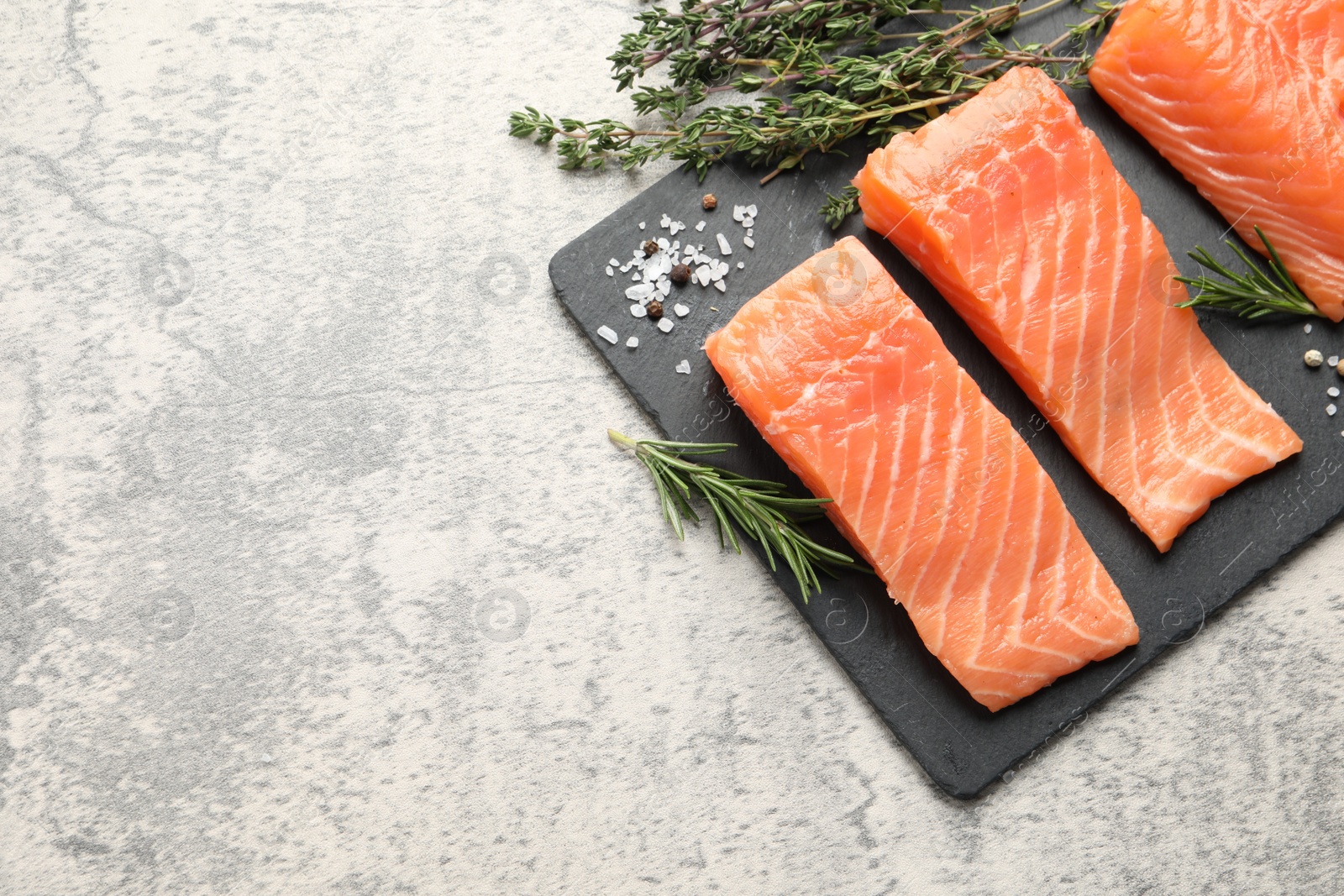 Photo of Fresh raw salmon and herbs on light grey table, flat lay. Space for text