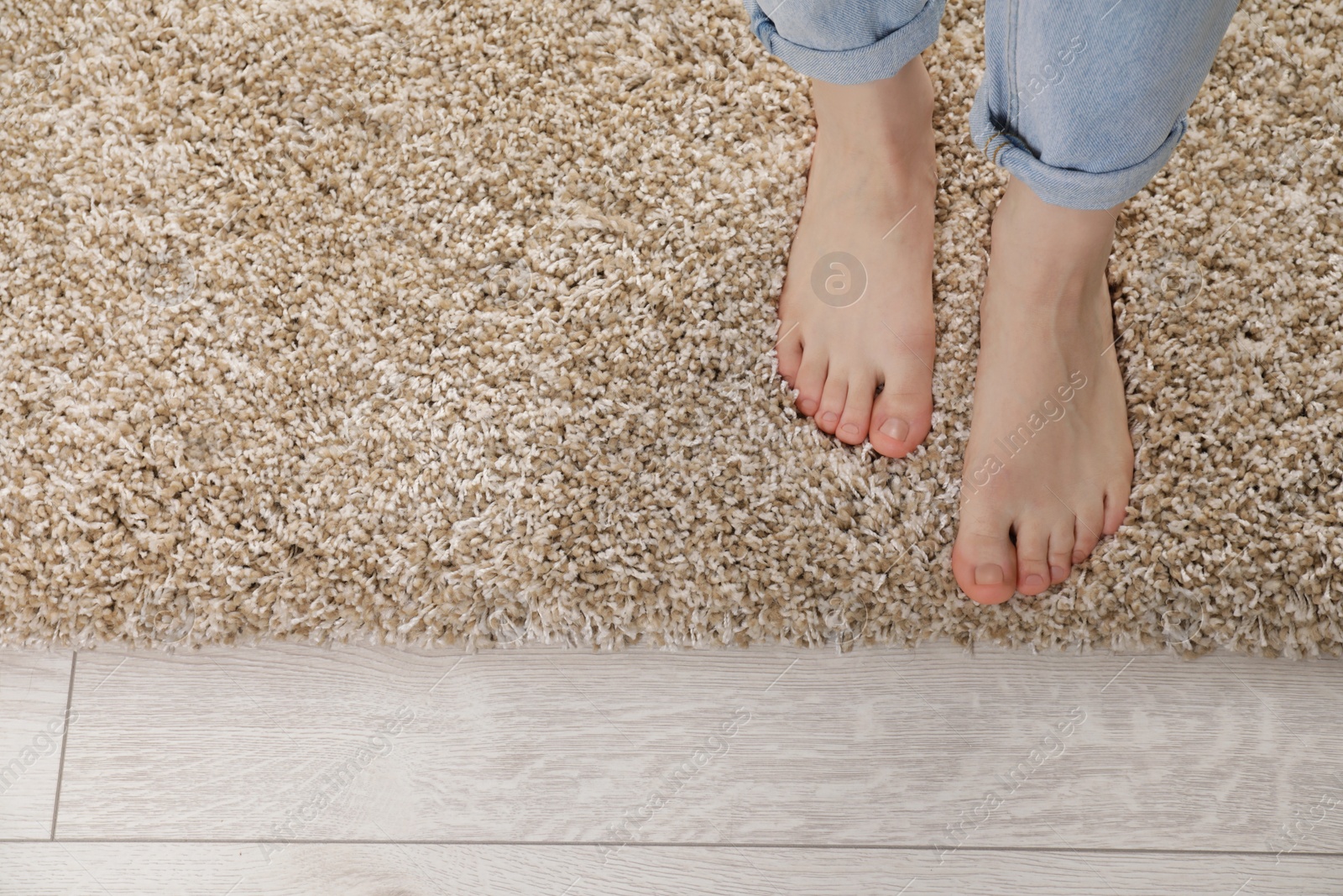 Photo of Woman standing on soft carpet at home, top view