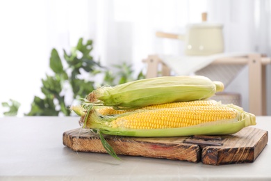 Photo of Tasty sweet corn cobs on wooden board