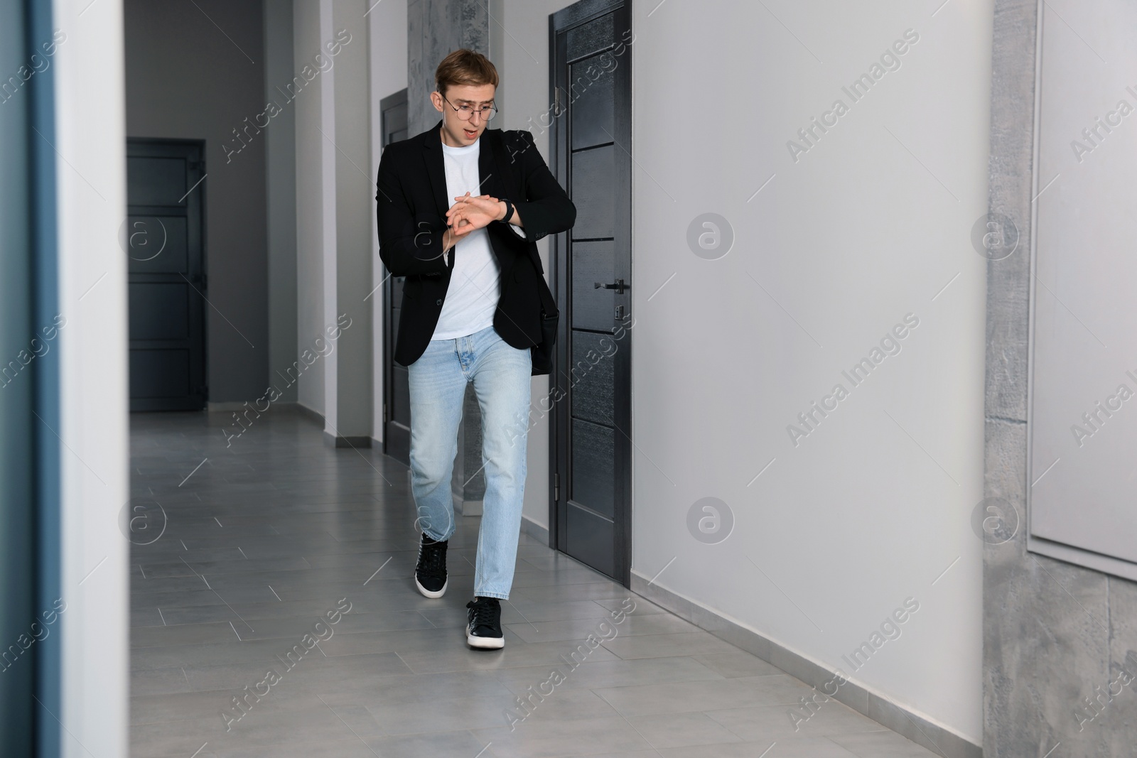 Photo of Emotional man checking time in hall. Being late