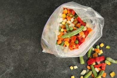 Photo of Zip bag with different frozen vegetables on grey table, top view. Space for text