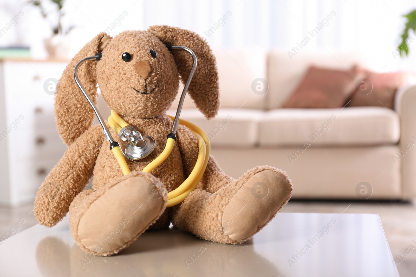 Photo of Stuffed bunny on table in child hospital. Space for text