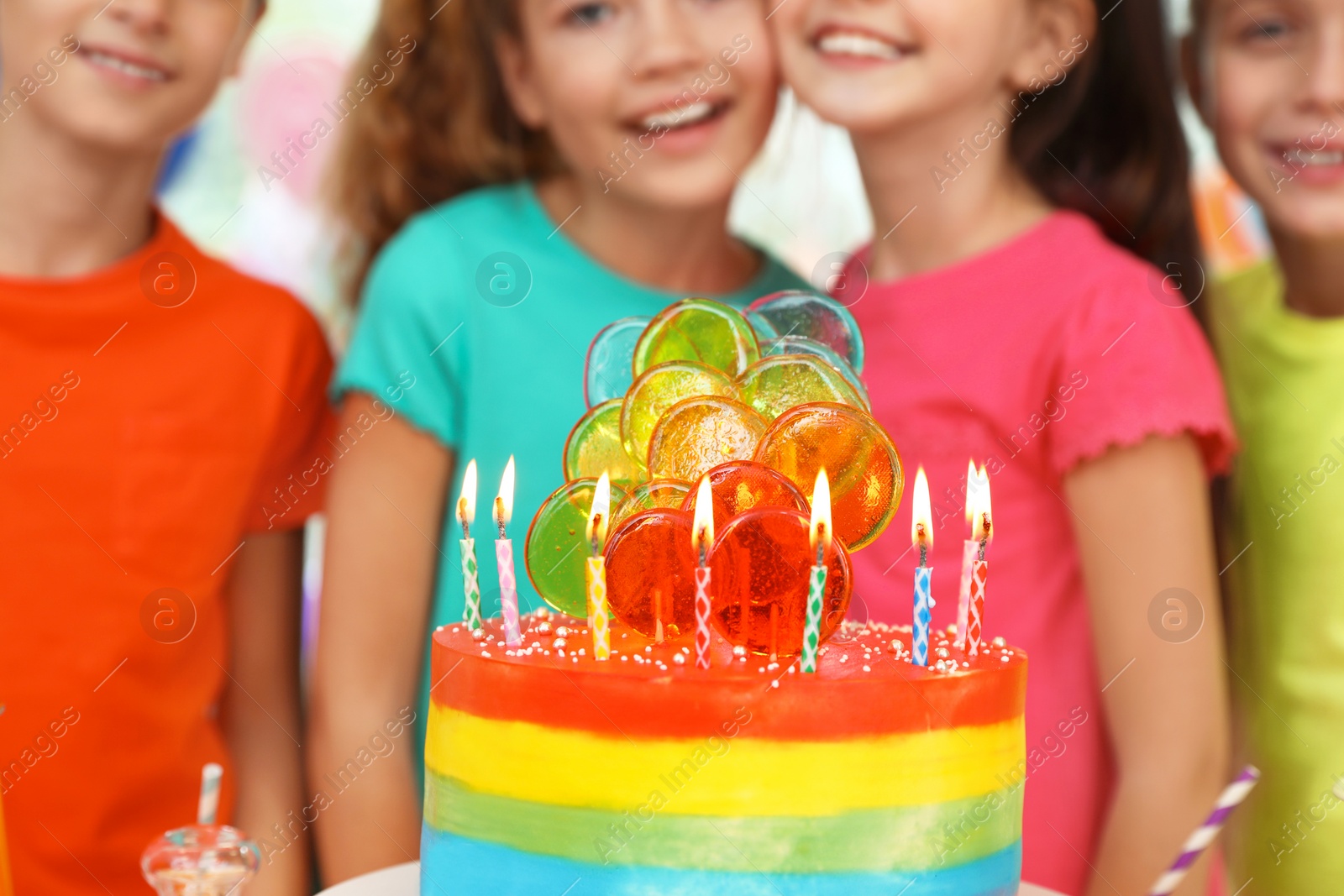 Photo of Children near cake with candles at birthday party indoors, closeup