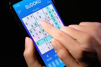 Image of Woman playing sudoku game on smartphone, closeup
