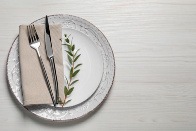 Photo of Stylish setting with cutlery and eucalyptus leaves on white wooden table, flat lay. Space for text