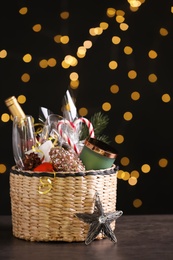 Photo of Wicker basket with Christmas gift set on grey table against festive lights