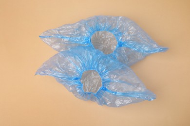 Photo of Pair of blue medical shoe covers on beige background, top view