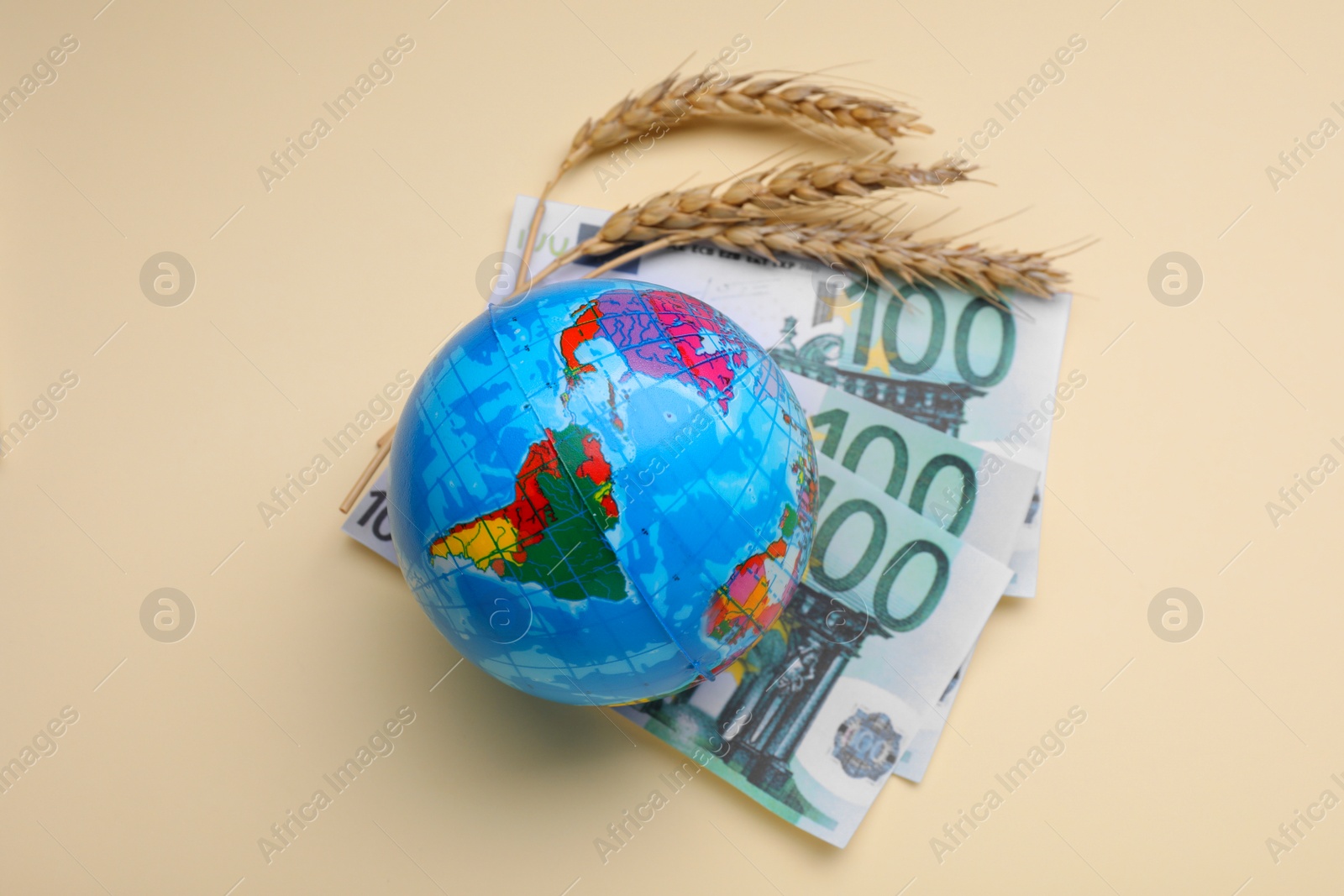 Photo of Import and export concept. Globe, ears of wheat and banknotes on beige background, flat lay