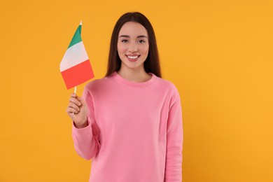 Photo of Young woman holding flag of Italy on orange background