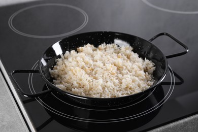 Photo of Cooking tasty rice on induction stove in kitchen, closeup