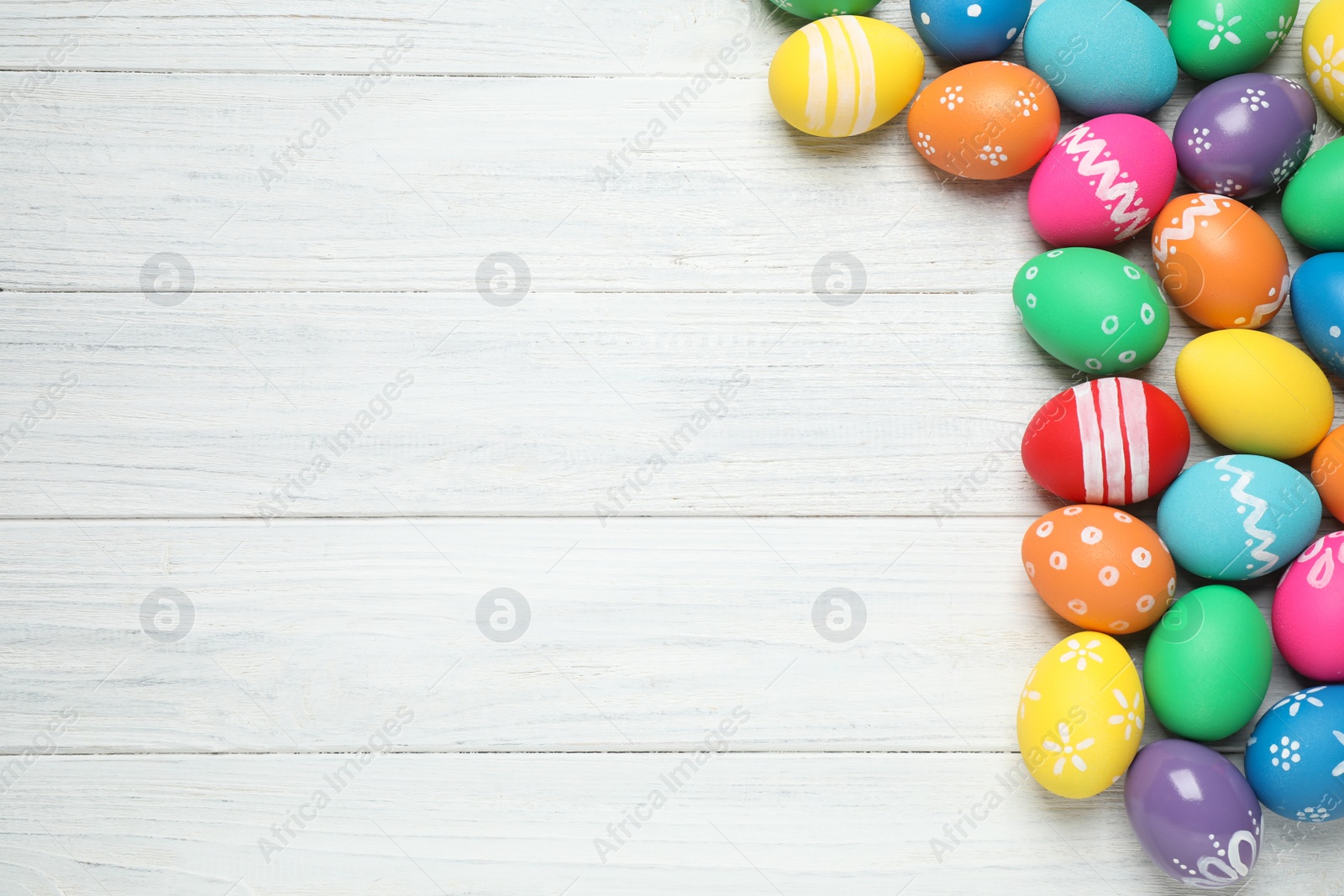 Photo of Many bright Easter eggs on white wooden background, flat lay. Space for text