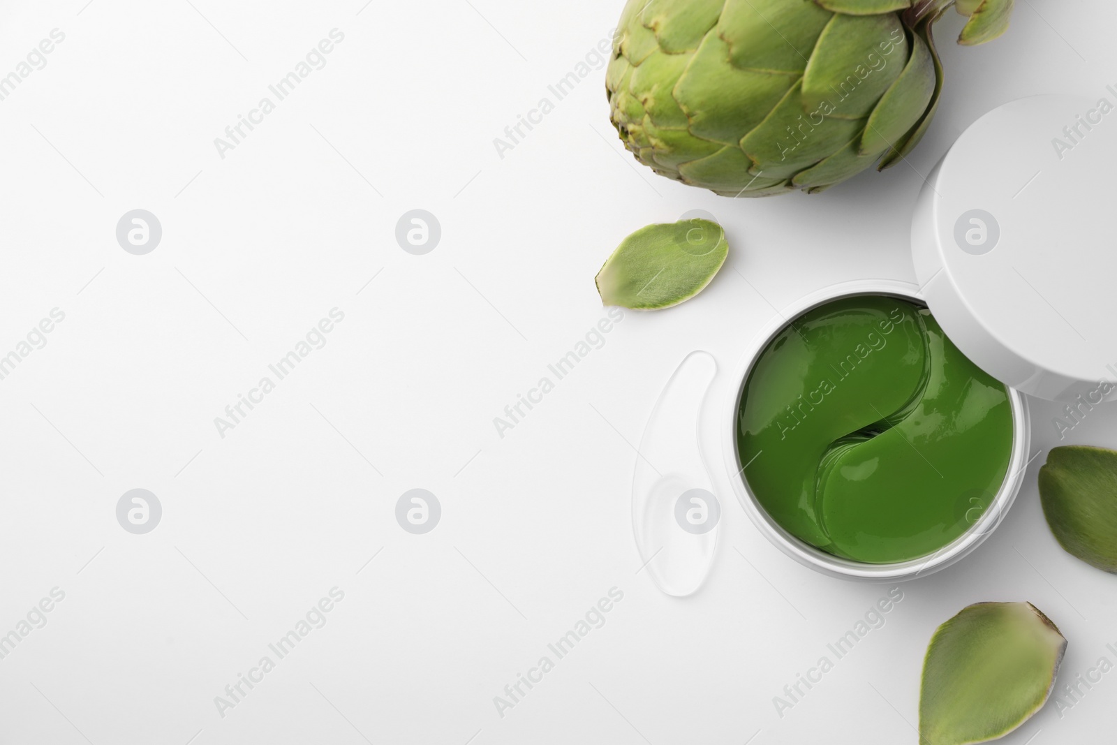 Photo of Package of under eye patches and artichokes on white background, top view. Cosmetic product