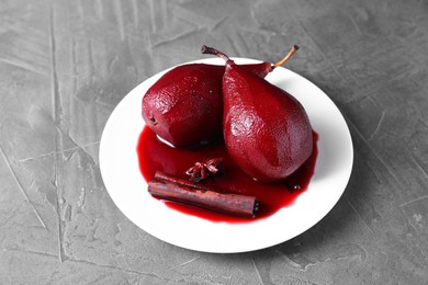 Photo of Tasty red wine poached pears and spices on grey table