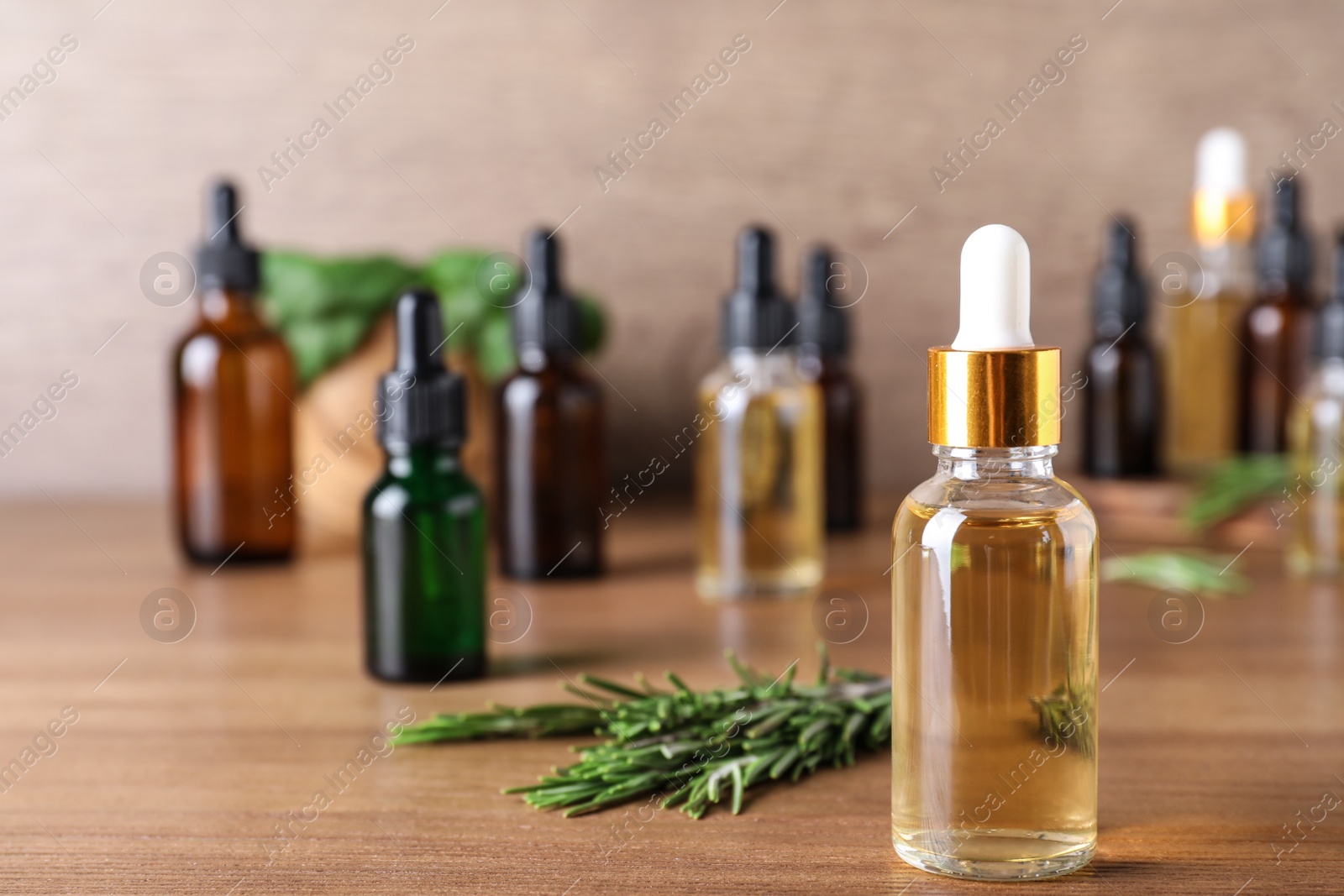 Photo of Bottle of rosemary essential oil on wooden table. Space for text