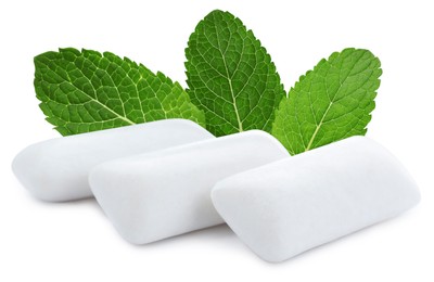 Menthol chewing gum pillows and mint leaves on white background