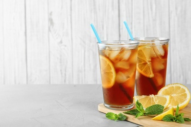 Photo of Glasses of refreshing iced tea on light table against white wooden background. Space for text