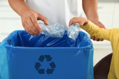 Father and son sorting garbage in kitchen, closeup. Recycling concept