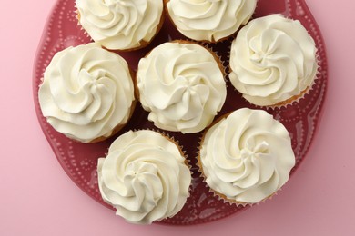 Tasty vanilla cupcakes with cream on pink background, top view