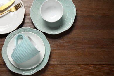 Photo of Beautiful ceramic dishware, cup and cutlery on wooden table, flat lay. Space for text