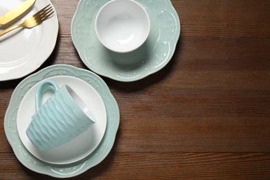 Beautiful ceramic dishware, cup and cutlery on wooden table, flat lay. Space for text