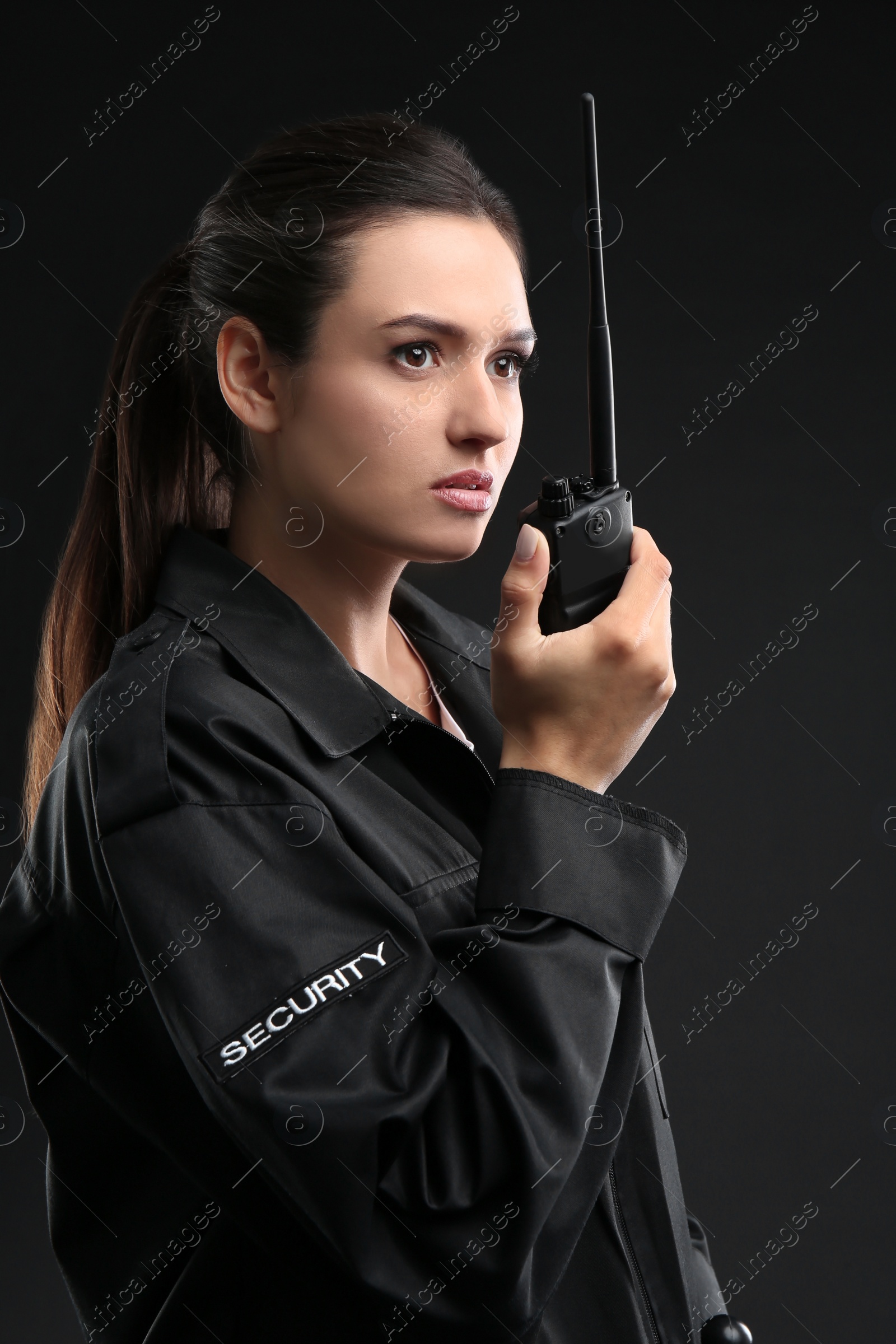 Photo of Female security guard using portable radio transmitter on dark background