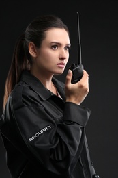 Photo of Female security guard using portable radio transmitter on dark background