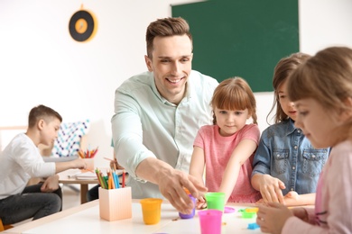 Photo of Cute little children with teacher in classroom at school