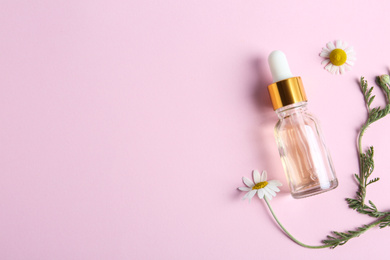 Photo of Bottle of essential oil and chamomiles on pink background, flat lay. Space for text