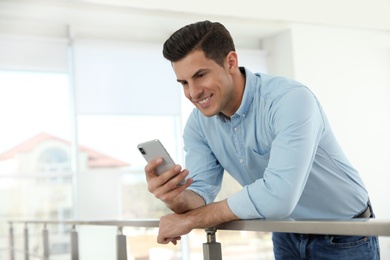 Photo of Portrait of handsome man with mobile phone in light room