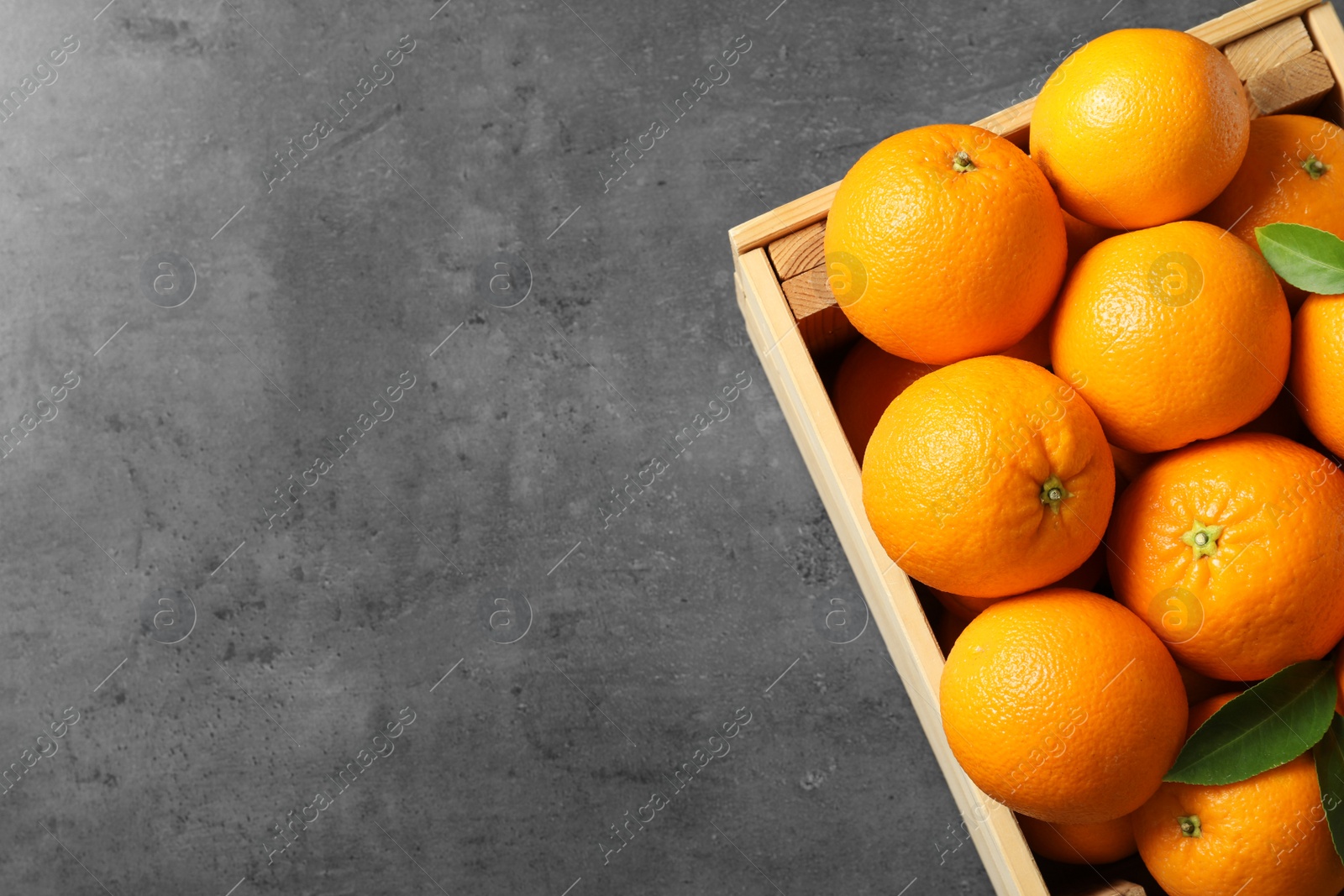 Photo of Wooden crate with ripe oranges on grey background, top view. Space for text