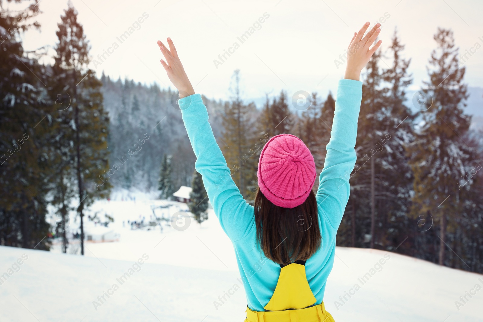 Photo of Young woman at mountain resort, back view. Winter vacation