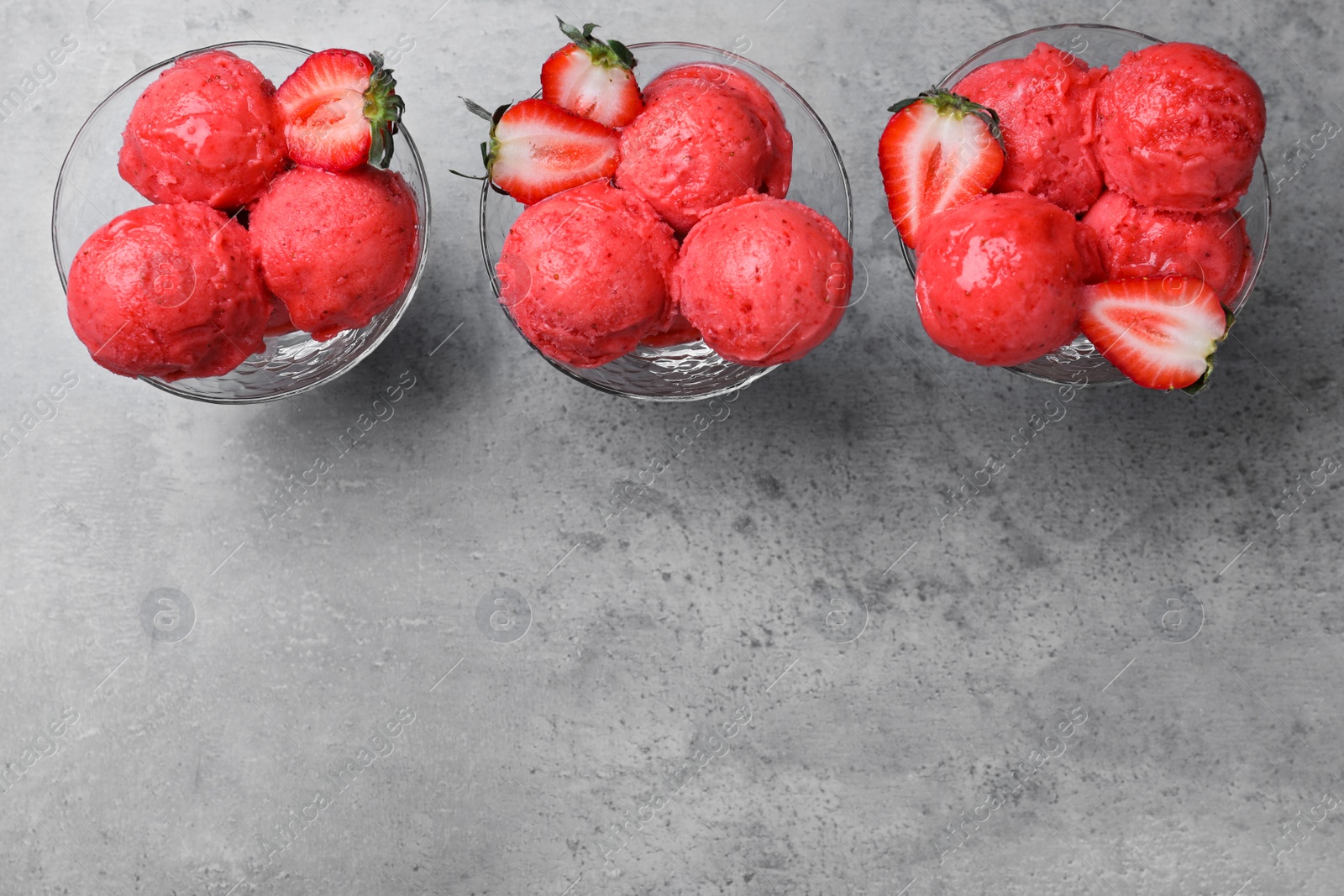 Photo of Delicious strawberry ice cream in dessert bowls on grey table, flat lay. Space for text