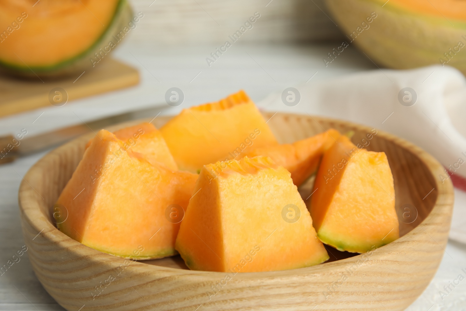 Photo of Pieces of tasty melon on wooden plate, closeup