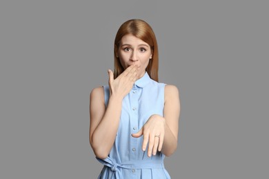 Emotional woman with engagement ring on light grey background