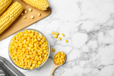 Delicious canned corn in bowl on marble table, flat lay. Space for text