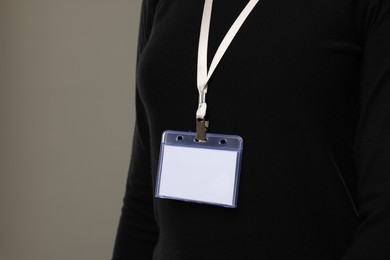 Woman with blank badge on grey background, closeup