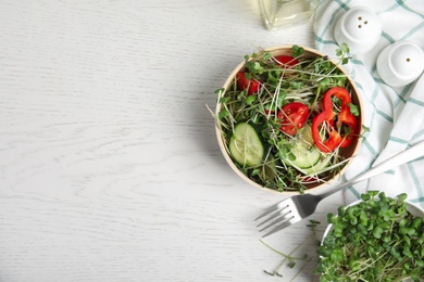 Photo of Salad with fresh organic microgreen in bowl on white table, flat lay. Space for text