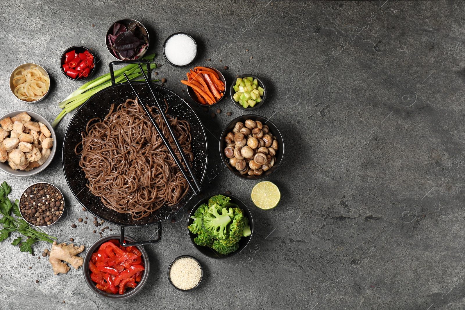 Photo of Wok with noodles, chicken and other products on grey table, flat lay. Space for text