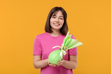 Photo of Easter celebration. Happy woman with wrapped egg on orange background