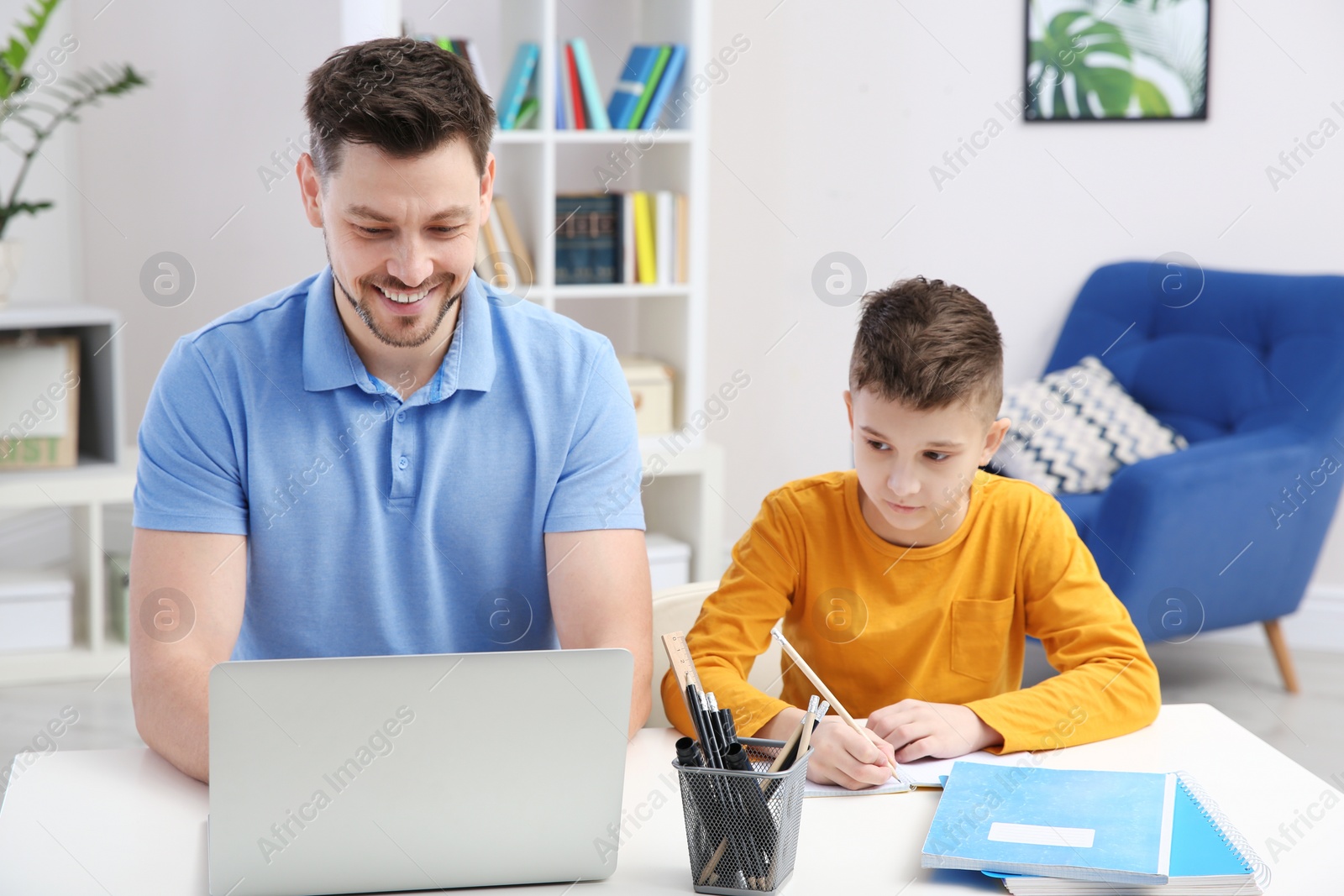 Photo of Dad helping his son with homework in room