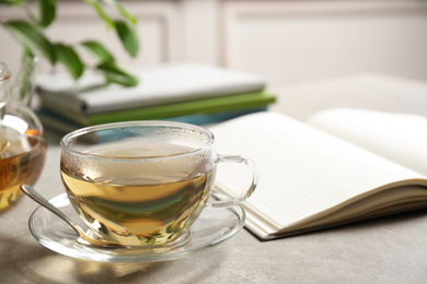 Photo of Tasty hot green tea in cup on grey table