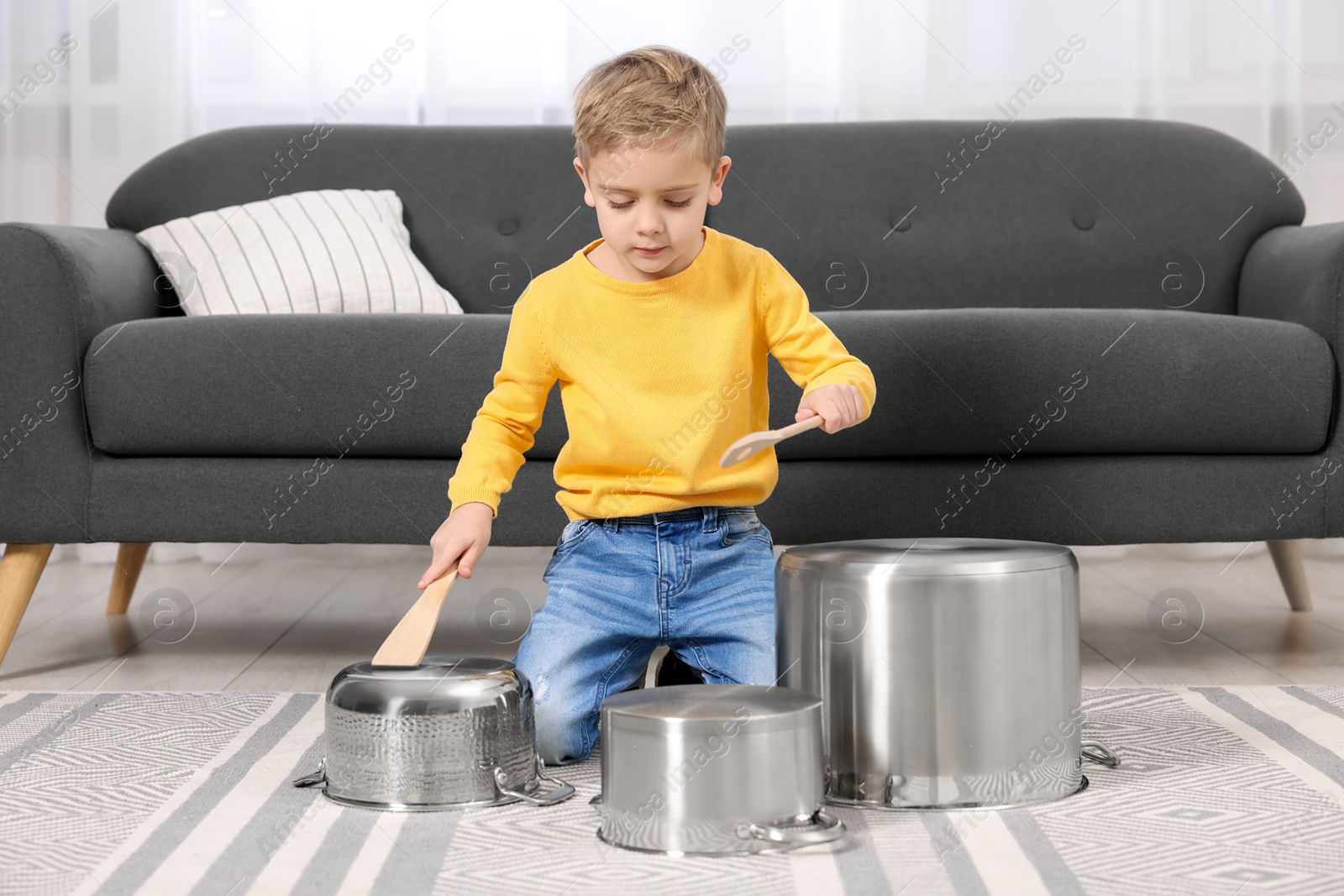 Photo of Little boy pretending to play drums on pots at home