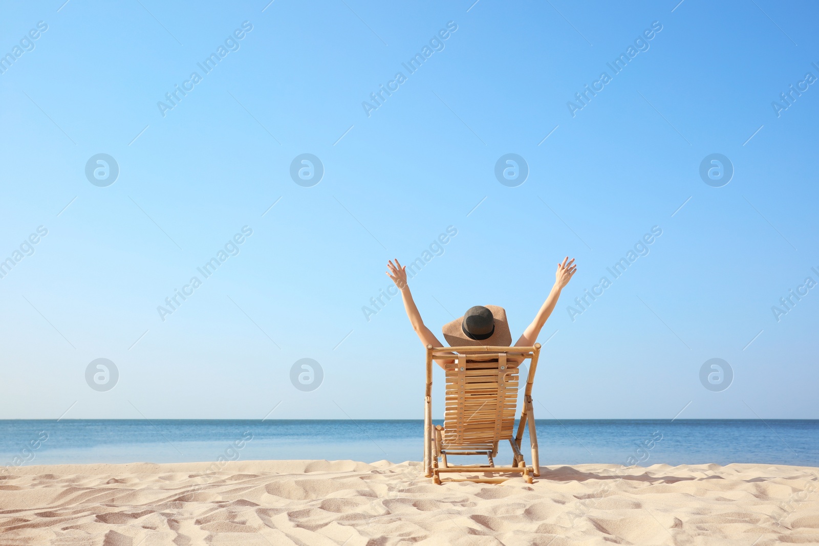 Photo of Young woman relaxing in deck chair on sandy beach