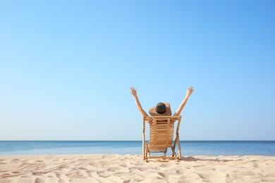 Photo of Young woman relaxing in deck chair on sandy beach