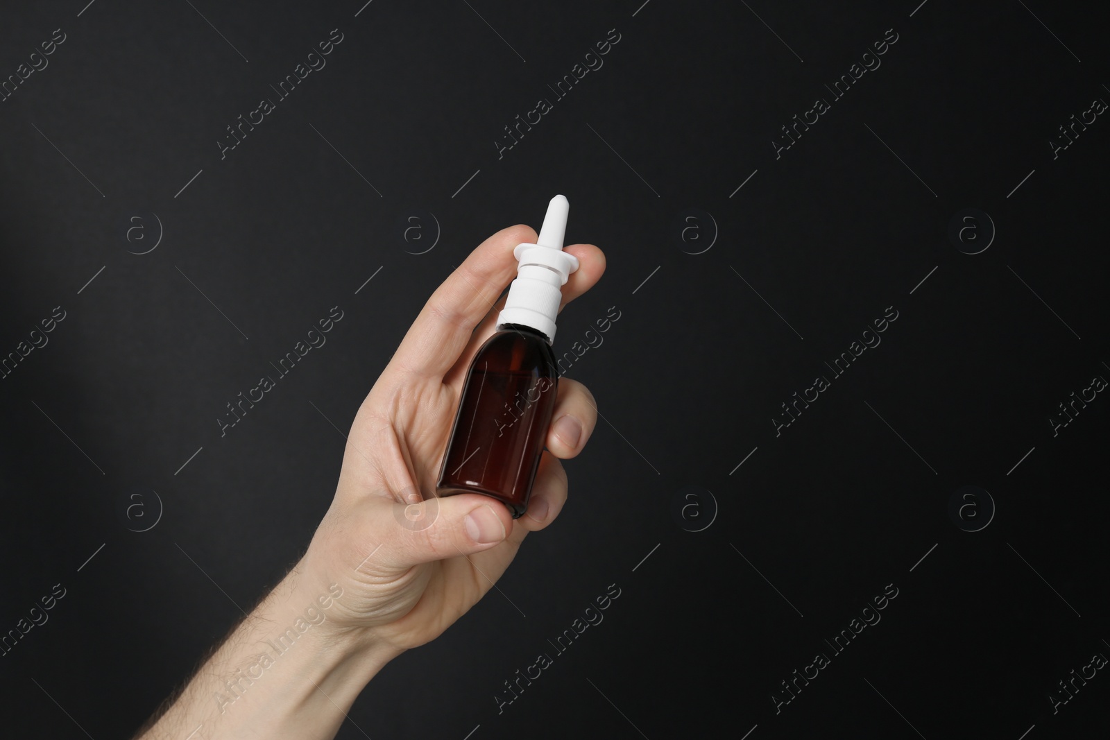 Photo of Man holding nasal spray on black background, closeup. Space for text