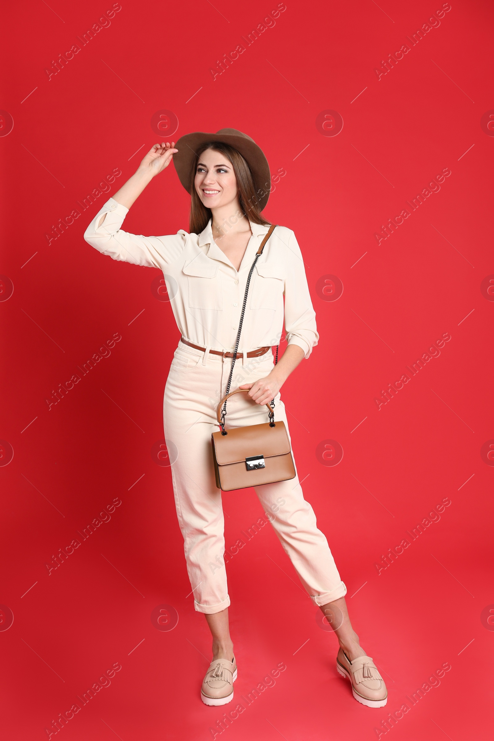 Photo of Beautiful young woman in casual outfit with stylish bag on red background