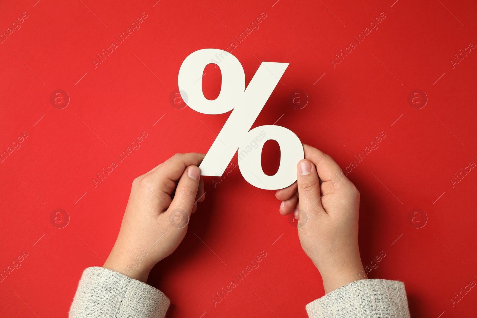 Photo of Man holding percent sign on red background, top view